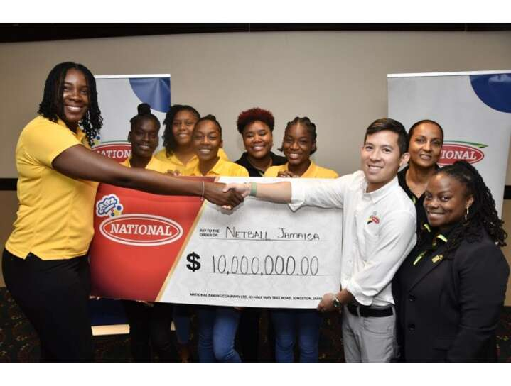 Director of sales and marketing of National Baking Craig Henderickson (second right) hands over his company's symbolic cheque to Sunshine Girls Captain Jhaniele Fowler during a press event at Jamaica Pegasus hotel in New Kingston recently. President of Netball Jamaica Tricia Robinson (right), along with other members of the Sunshine Girls team look on