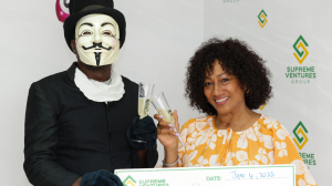 Lotto player, A. Lewis, collects his $190-million cheque from Heather Goldson (right), Chief Marketing Officer Supreme Ventures Group, during the official handover of his lotto winnings.