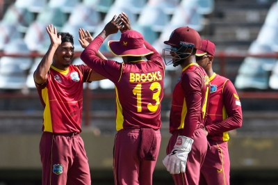 Gudakesh Motie (left) celebrates with his West Indies teammates.