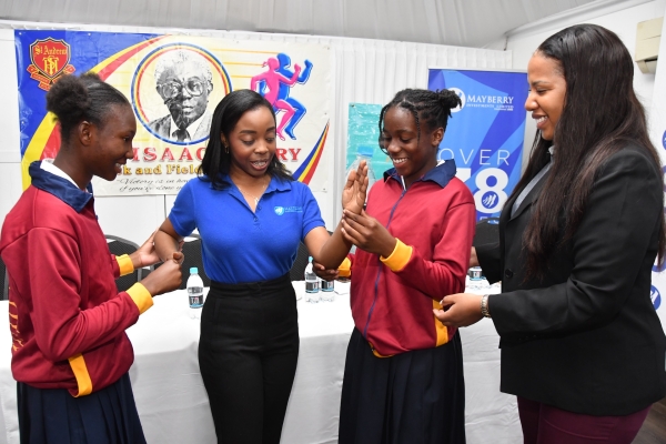 Desiree Wheeler, Senior Marketing Officer at Mayberry Investments (second from the left), gains insights from track stalwarts Jadeish Maragh, a student at St. Andrew Technical High School (left), and Phillancia Pounall (third from the right). Ayawna Morgan, Category Manager of Beverages and Snacks at iCOOL Jamaica (right), savours the moment during the launch of the S.W. Isaac-Henry Track and Field Invitational on Friday.