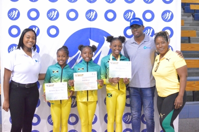 Jamaican Gymnastics Team (from centre-left to right): Elyssa Pamella, Alexi Zuri Mantadara, and Mariah Macera Gordon proudly showcase their achievements, flanked by Mayberry Investments Limited’s (MIL) Investment Advisor Shanice Williams (left), Horace Collins (second right), and Nicole Grant, President of the Jamaica Gymnastics Association (right).